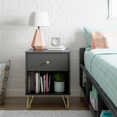 a nightstand with books on it next to a bed in a room that has white brick walls