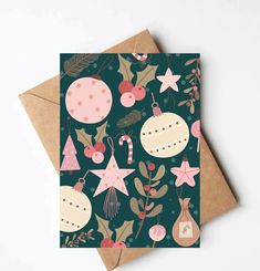 a card with christmas ornaments and stars on it, sitting on top of a brown envelope