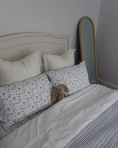 a teddy bear sitting on top of a bed next to pillows and pillowcases