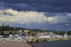 storm clouds loom over a marina with boats in the water and houses on the shore