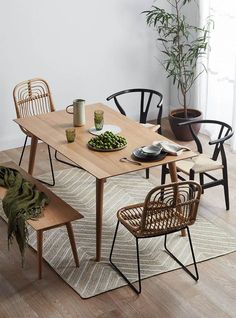 a wooden table with chairs around it and a potted plant in the corner next to it