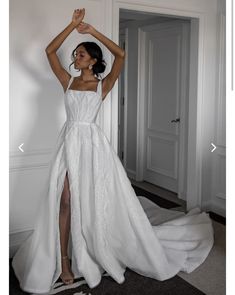 a woman in a white wedding dress is posing for the camera with her arms up