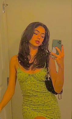 a woman in a green dress taking a selfie