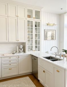 a kitchen with white cabinets and gold handles on the sink, dishwasher and oven