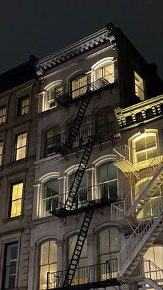 a fire escape is lit up at night in front of a large building with many windows