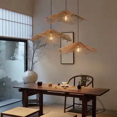 a dining room table with chairs and lights hanging from it's ceiling over it