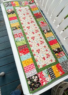 a quilted table runner sitting on top of a white chair next to a deck