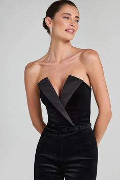 a woman wearing black velvet jumpsuits with an asymmetrical bow at the waist