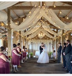 a bride and groom standing in front of their wedding party at the end of an aisle