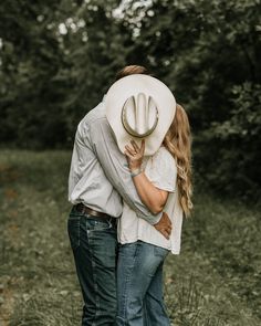 a man and woman embracing each other with a cowboy hat on their head