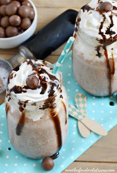 two glasses filled with ice cream and chocolate on top of a blue napkin next to spoons