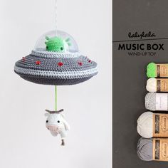 a crocheted toy with an alien hat hanging from it's side next to yarn rolls