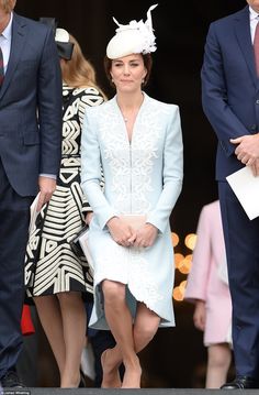 a woman in a blue dress and hat walking out of a building with other people