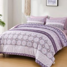 a bed with purple and white comforters in a room