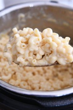 a spoon full of macaroni and cheese being held over the top of it