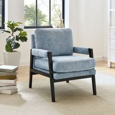 a blue chair sitting in front of a window next to a potted plant and books