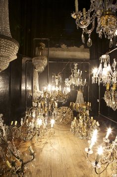 a room filled with lots of chandeliers hanging from it's ceiling and wooden floors