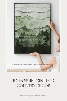 a woman is holding up a painting with trees on it and the words, john murprint for country decor