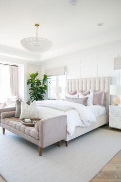 a large white bed sitting in a bedroom next to a window