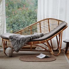 a rattan chaise lounge chair in front of a window