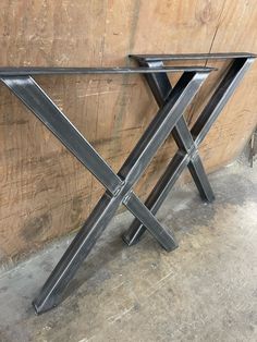 a metal table sitting on top of a cement floor next to a wooden plank wall