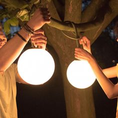 two people are holding up some lights in the dark, while one person holds on to another