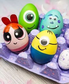 three eggs with faces painted on them sitting in an egg carton next to two smaller ones