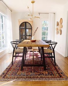 a dining room table with chairs and a rug on the floor