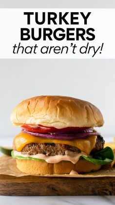 a turkey burger with lettuce, onions and tomato on a cutting board