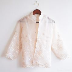 An embroidered organza Filipiniana jacket created by the artisans of Lumban, the capital of hand embroidery in the Philippines. Exquisitely made with Sampaguita floral details. A wonderful heirloom piece. DETAILS Size: Medium (Approx 38" bust) Make: Natural white, semi-sheer organza, machine sewn and embroidered. Each garment is individually handmade. Slight variations in embroidery make each blouse special. Care: Hand wash and air dry flat only. Do not wring. To press, use a cotton pressing clo Embroidered Organza Blouse For Wedding, Traditional Organza Blouse With Floral Embroidery, Organza Blouse With Floral Embroidery For Wedding, Elegant Floral Embroidered Fabric For Traditional Ceremonies, Organza Wedding Blouse With Floral Embroidery, Wedding Organza Blouse With Floral Embroidery, Wedding Blouse With Floral Embroidery In Organza, Embroidered Long Sleeve Organza Blouse, Spring Embroidered Organza Blouse