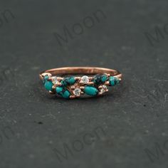 a gold ring with turquoise stones and diamonds on the bottom, sitting on a black surface