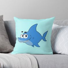 a blue shark with big eyes on it's face sitting on a couch throw pillow