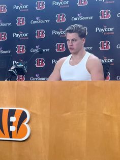 a man standing at a podium in front of a wall with a tiger logo on it