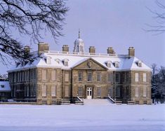 an old brick building with snow on the ground and trees in front of it,