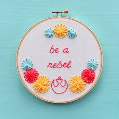 a hand embroidered hoop with flowers and the words be a nicer written in red on it