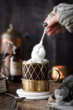 a person is spooning whipped cream into a cup on a table with other items