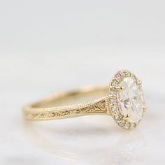 a close up view of a yellow gold engagement ring with an oval cut diamond in the center