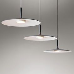 three circular lights hanging from the ceiling in a room with gray walls and flooring