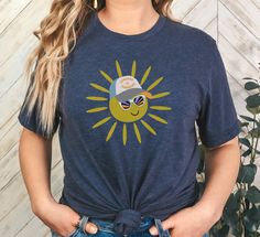 Add a splash of humor and sunshine to your wardrobe with our Sunshine and Rainbows T-Shirt! Featuring a playful sun graphic wearing sunglasses with a rainbow reflection and a cap that reads "Sunshine and Rainbows," this tee is perfect for those who love to spread positive vibes--or a bit of sarcasm. Whether you take it literally or with a wink, this design is sure to brighten your day. Crafted from high-quality materials, this unisex tee ensures both comfort and durability. It's perfect for summ Casual Uv Protection Tops For Beach Season, Casual Tops With Uv Protection For Beach Season, Casual Uv Protection Tops For Vacation, Casual Tops With Uv Protection For Vacation, Casual Vacation Tops With Uv Protection, Summer Outdoor Tops With Uv Protection, Outdoor Summer Tops With Uv Protection, Casual Crew Neck Tops With Uv Protection, Uv Protection Summer Outdoor Tops