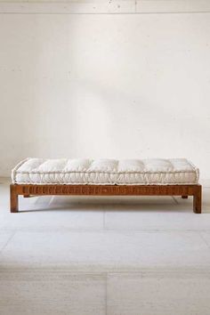 a wooden bench sitting in the middle of a room next to a window with white walls