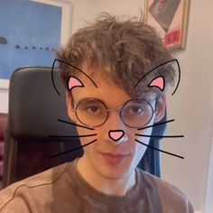 a young man wearing glasses with a cat's face drawn on the side of his face