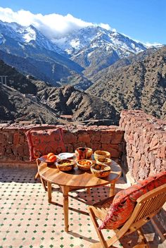 a table and chairs on a patio with mountains in the background