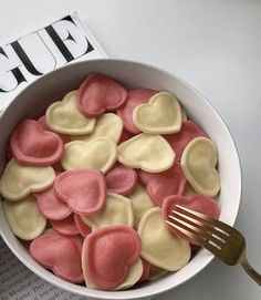 a bowl filled with heart shaped cookies next to a magazine