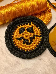 an orange and black crochet doily next to a yellow thread spool