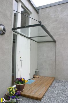 a wooden deck with potted plants and flowers on the ground next to a white door