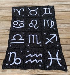 a black rug with white letters and numbers written in chalk on top of wooden floor