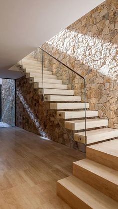 there is a stone wall and wooden stairs in this house with wood flooring on both sides