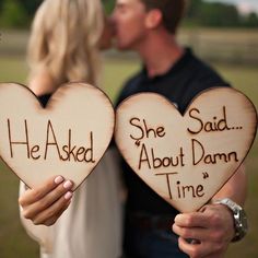 two people holding wooden hearts that say he asked, she said about damn and time