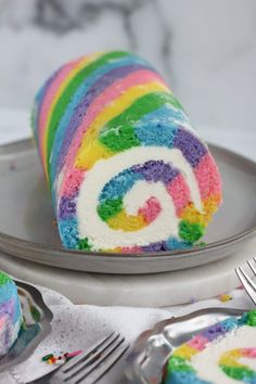 a slice of rainbow swirl cake on a plate with a fork and knife next to it