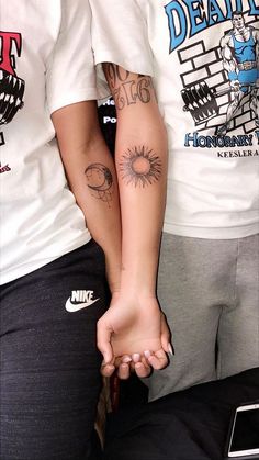 two people holding hands with tattoos on their arms